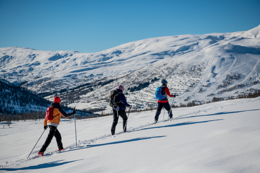 Tre kvinner på fjellski i laussnø med Myrkdalen Fjellandsby i bakgrunnen
